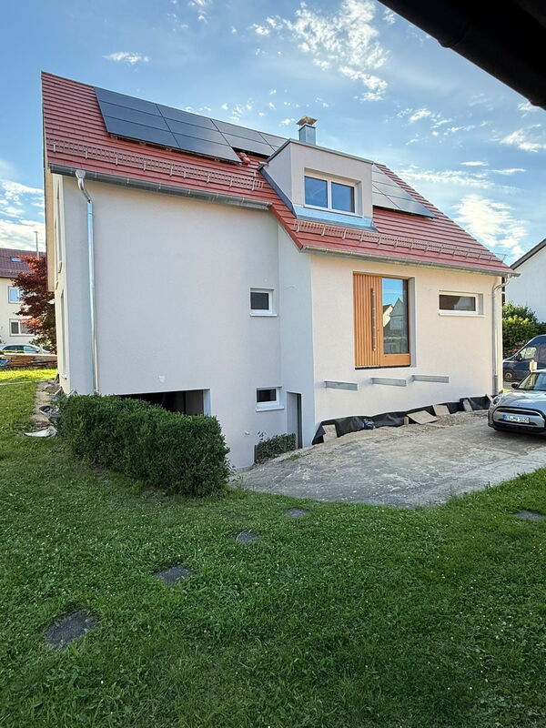 Fertig gedämmte Fassade mit Holz-Haustür – Eingangsseite
